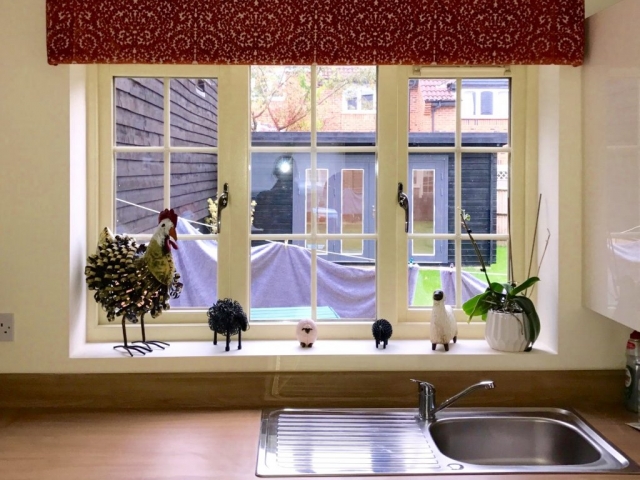 Upholstered decorative pelmet in a burnt orange textured pattern with voile roller blind behind