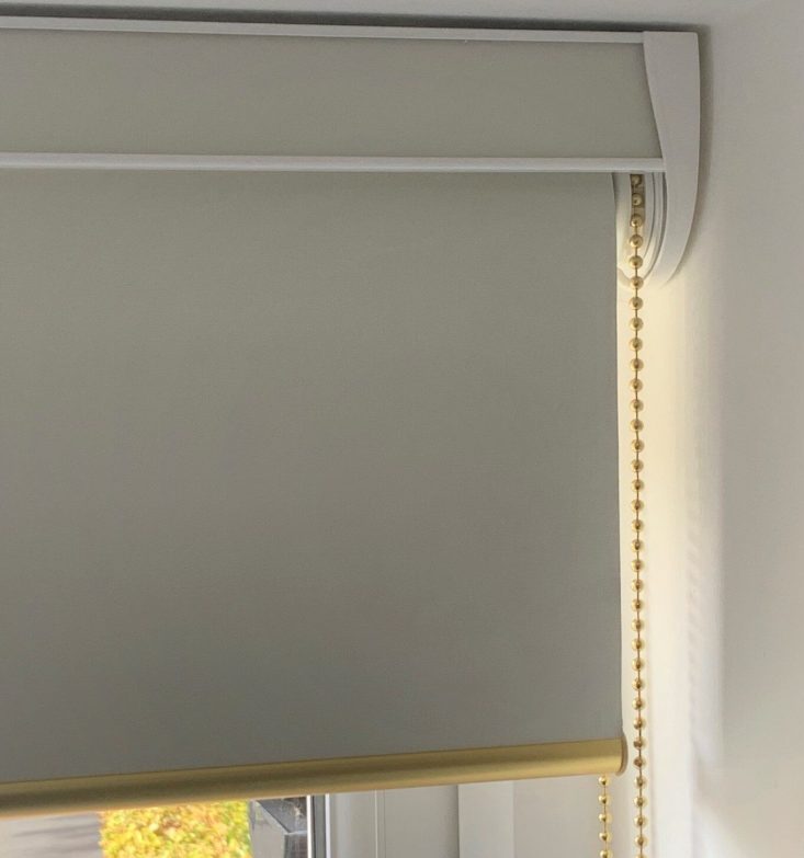 Fascia roller blind in blockout fabric, with brass chain control and brass round bottom bar, installed in Welwyn Garden City