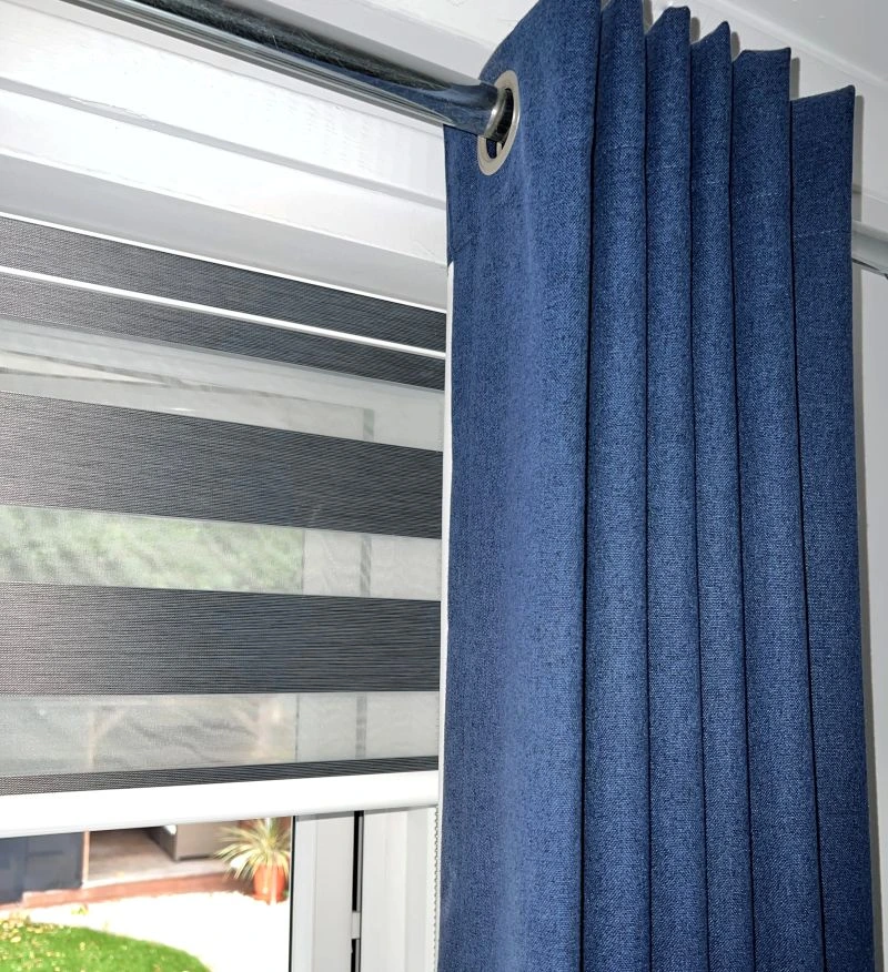 Day and Night Roller blind in dark grey with Deep Indigo Eyelet curtains in front