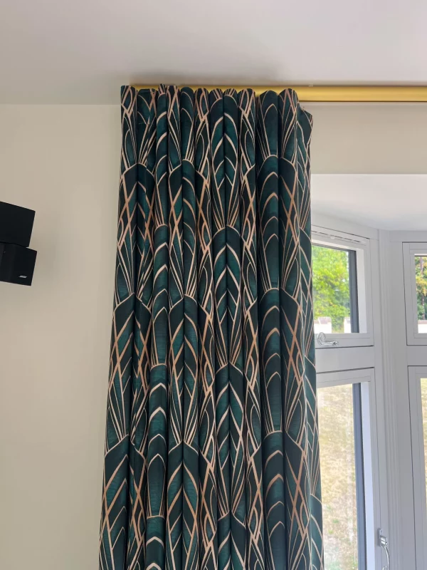 Wave Curtains in Art Deco patterned velvet fabric with 80mm Wave headings, ceiling mounted on brushed gold finish tracked pole. Installed in a St Albans living room