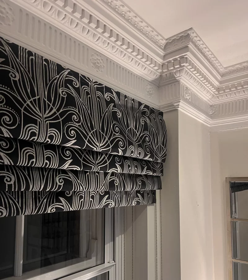 Roman blind with waterfall heading, in Arcadia Art Deco fabric in black, installed in a period property in Hertford