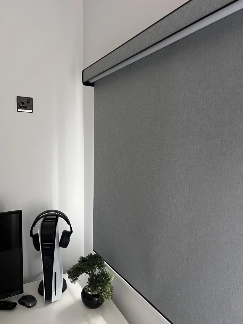 Roller blind with black aluminium fascia headbox and textured blockout fabric in a bedroom