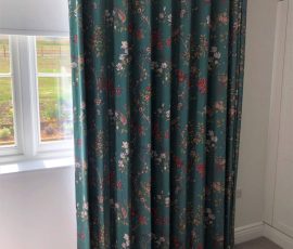 Floor to ceiling 80mm wave curtains on a Silent Gliss white uncorded track, with curtains in a deep green Japanese inspired print