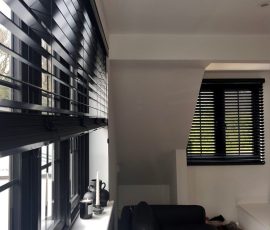 Black painted wood venetian blinds with 50mm wide slats in a modern living room